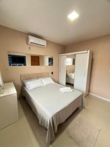 une chambre avec un grand lit blanc et un réfrigérateur dans l'établissement Acomodação para COP30, à Belém