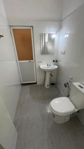 a white bathroom with a toilet and a sink at Green Wall House in Dickwella