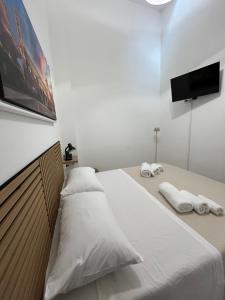 a bedroom with a bed with white sheets and a flat screen tv at D'Aversa Rooms in Marineo +3 photos