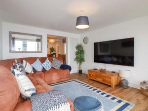 a living room with a brown leather couch and a flat screen tv at Ocean Edge in Sennen Cove