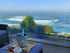 a table with wine glasses and a view of the ocean at Ocean Edge in Sennen Cove