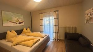 Un dormitorio con una cama con almohadas amarillas y una ventana. en Appartements Sigmair, en Valdaora