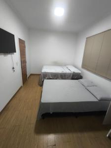 a room with two beds and a flat screen tv at Varanda das araras in Manaus