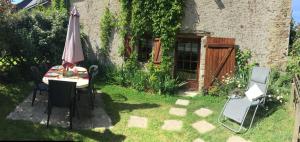 a table and chairs and an umbrella in a yard at Gîte à la ferme I An Ti Ar Sav Heol in Sarzeau +9 photos