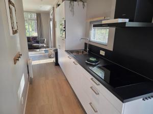 a kitchen with white cabinets and a black counter top at Natuurhuisje Hellendoorn in Haarle