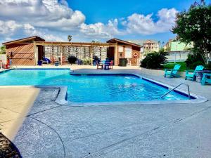 a swimming pool with blue chairs and a house at Shoreline Studio Condo for 4 in Galveston