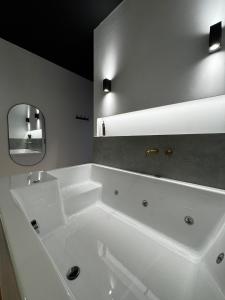 a white bathroom with a tub and a mirror at Botanica Noir Jacuzzi Valaoritou in Thessaloniki +14 photos