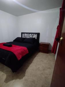 een slaapkamer met een zwart bed en een rode deken bij Apartment in Bogotá in Bogota