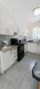 een keuken met witte kasten en zwarte apparaten bij Muizenberg lakeside in Lakeside