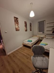a room with two beds and a chair in it at Apartament Jana in Warsaw