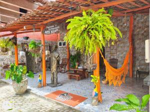 een buitenterras met een palmboom en een tent bij Pousada Meu Xodó in São Miguel dos Milagres