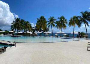 una gran piscina con palmeras y sombrillas en Pause tropicale, en Le Diamant 2 fotos más