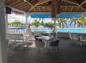 un restaurante con mesa, sillas y piscina en Pause tropicale, en Le Diamant