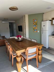 een houten eettafel met stoelen en een witte koelkast bij Cambllis in Bombinhas