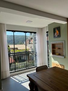 een eetkamer met een tafel en een groot raam bij Cambllis in Bombinhas