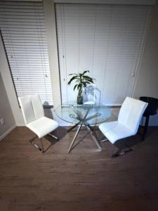 un tavolo di vetro con due sedie bianche e una pianta in vaso di Townhome with fish Tank & Private Garage a Portland