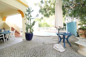 a patio with an umbrella and tables and a potted plant at Alcaria Pool House in Altura