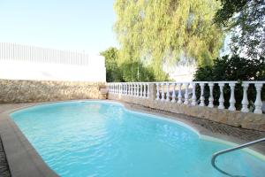 a large blue swimming pool next to a stone fence at Alcaria Pool House in Altura