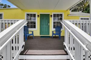 een geel huis met twee blauwe stoelen op een veranda bij Southern Comfort - For 6 Guests in Gulf Stream