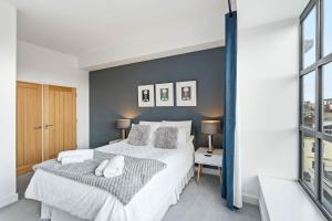 ein Schlafzimmer mit einem großen Bett mit einer grauen Wand in der Unterkunft Castle View By Ginger & Gold Luxury Norwich Apt in Norwich