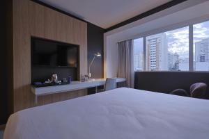 a hotel room with a bed and a large window at eSuites Savassi Toscanini in Belo Horizonte +63 photos