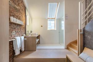 a bathroom with a sink and a brick wall at DeuxHommes in Hasselt