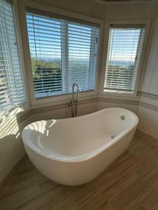 a white bath tub in a bathroom with windows at Bahamian Rhapsody of Hopetown, Elbow Cay, Abaco,BA 