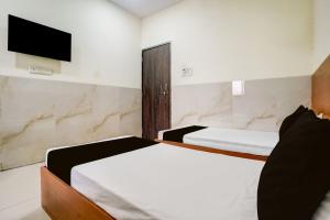a bedroom with two beds and a tv on the wall at Hotel O Balaji Hotel & Banquet in Boisar