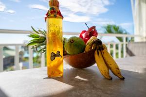 a bowl of fruit with a bottle and a bowl of bananas at Appartement Coconut in Saint-François