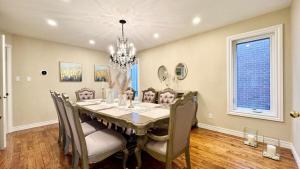 ein Esszimmer mit Tisch und Stühlen und einem Kronleuchter in der Unterkunft Designer 4BR Retreat, Luxe Living & Family-Friendly Fun in Mississauga
