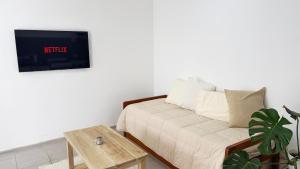 a living room with a couch and a tv on a wall at Temporario Sur, hasta 4 personas con 3 camas, General Roca in General Roca