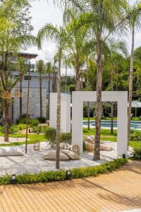 ein großes weißes Schild in einem Park mit Palmen in der Unterkunft Riviera | Luxo e Design no Golf – Cond Privativo in Riviera de São Lourenço