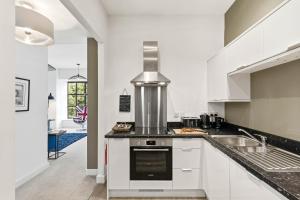 eine Küche mit weißen Schränken und einem Herd mit Backofen in der Unterkunft Castle View By Ginger & Gold Luxury Norwich Apt in Norwich
