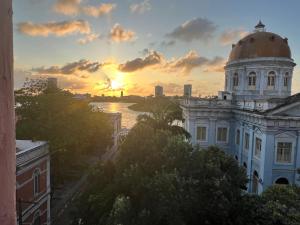 un edificio con una cupola in cima con un tramonto di Lindo nascer do Sol II a Recife
