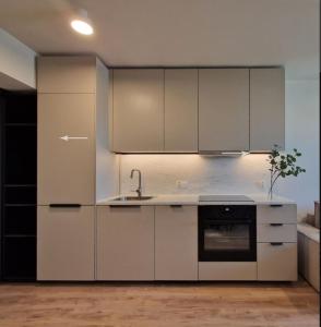 a kitchen with white cabinets and a sink at Apartament Podniebny z Windą in Kluczbork