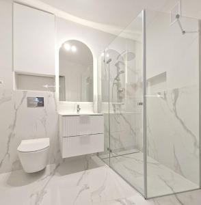 a white bathroom with a toilet and a shower at Apartament Podniebny z Windą in Kluczbork