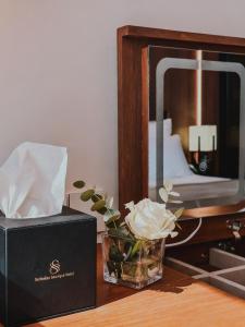 een vaas met bloemen naast een doos en een spiegel bij Serbellas Boutique Hotel in Paphos City