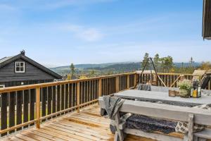 a wooden deck with a table on top of it at Hytte på Lygna med fantastisk utsikt in Gran