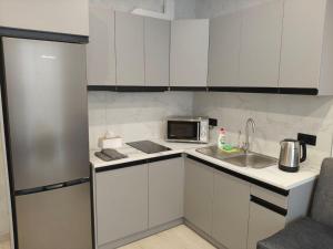 a kitchen with white cabinets and a sink and a microwave at New Suit Apartment in Hostomelʼ
