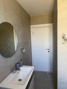 a bathroom with a sink and a mirror and a door at Estel Apartament in Tirana