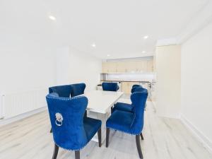 a dining room with a white table and blue chairs at Preston Street Apartments - by the Brighton i360 in Brighton & Hove