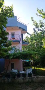 a pink building with a balcony and some trees at Deka apartments 5 in Fethiye
