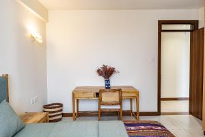 a room with a table with a vase of flowers on it at Diamond Ivy Two Bedroom Apartment, Swimming pool, gym, workspace ,Wonderiss Homes Kileleshwa Living in Nairobi