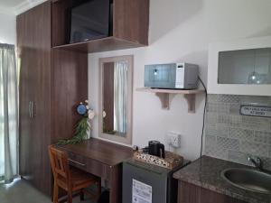 a kitchen with a desk and a sink and a microwave at Juliet Rose Luxury Guesthouse B&B in Bloemfontein