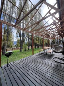 a pergola with a table and chairs on a deck at Cabaña entre alamos in Coihaique +12 photos