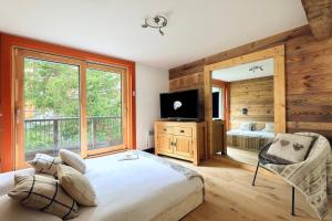 ein Schlafzimmer mit einem Bett, einem Fernseher und einem Fenster in der Unterkunft New new duplex apartment near runway in Saint-Bon-Tarentaise
