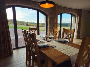 a dining room with a table and a large window at Remore Steading - Coachhouse in Ardclach