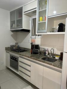 een keuken met witte kasten en een spoelbak bij Ap Villa Toscana in Ilhéus