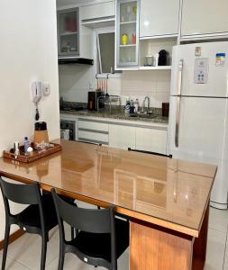 een keuken met een houten tafel en een koelkast bij Ap Villa Toscana in Ilhéus