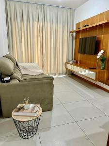 een woonkamer met een bank en een tafel bij Ap Villa Toscana in Ilhéus